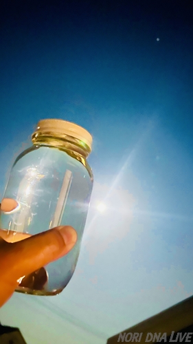 満月の夜に月光を浴びて作られたムーンウォーター。深い夜空を背景に、ガラス瓶の中の純粋な水が月のエネルギーを宿して輝いている。